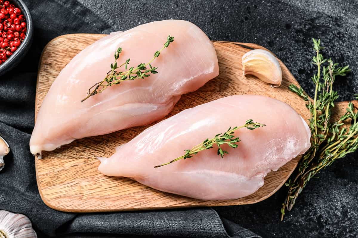 Pechugas de pollo crudas sobre una superficie oscura